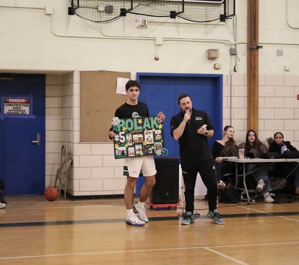 Harrison Polak holds his highlights poster during Senior Night.